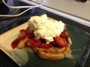 Mickey-shaped oat waffles, topped with sliced strawberries and whipped cream